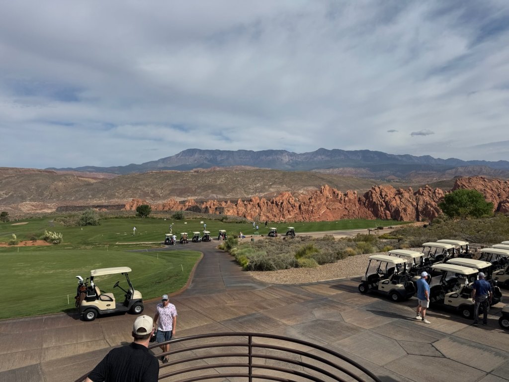 Golf carts lined up below the clubhouse at Sky Mountain Golf Course, Hurricane, Utah, with red cliffs and mountains in the distance