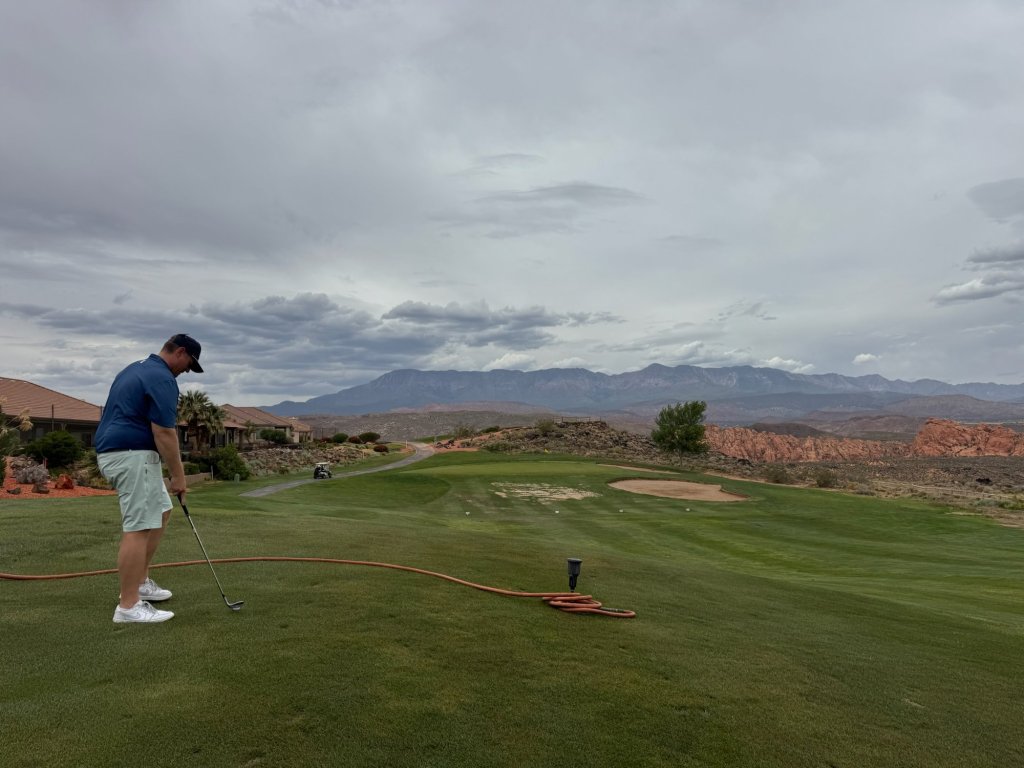 A golfer at address on a tee box at Sky Mountain Golf Course, Hurricane, Utah, under a cloudy sky