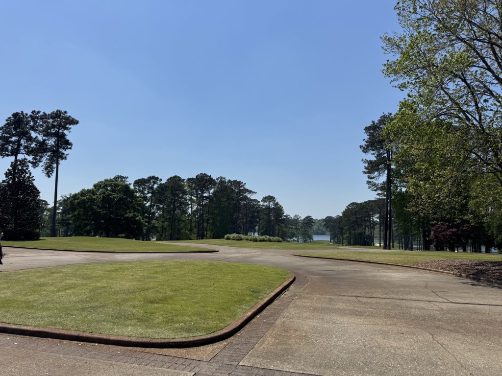 A practice green and pine trees under a clear blue sky at Grand National, Opelika, Alabama